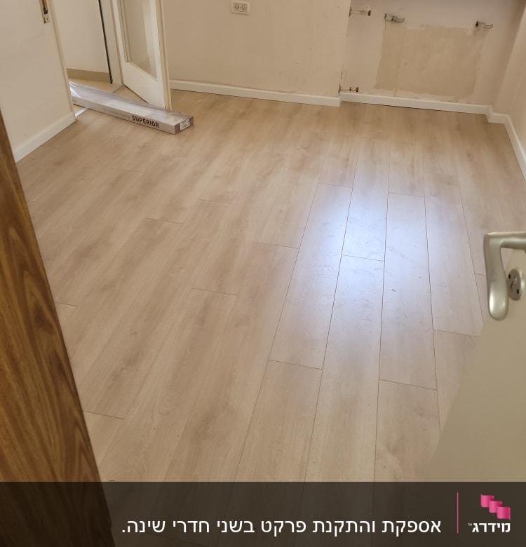 רצפת פרקט עץ בהירה בחדר ריק עם דלת פתוחה